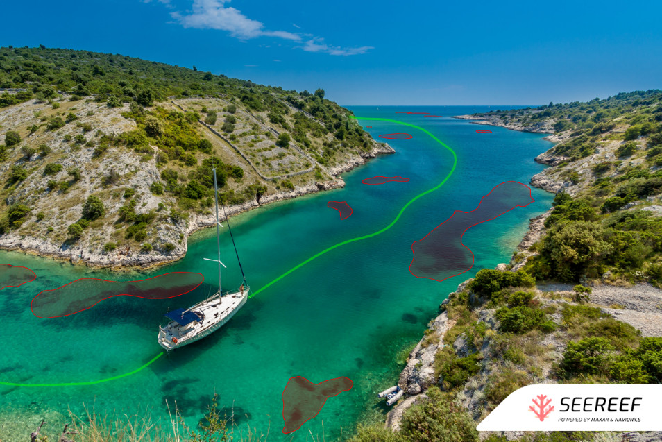 A yacht navigating a narrow inlet. A highlighted safe route and highlighted hazards can be seen